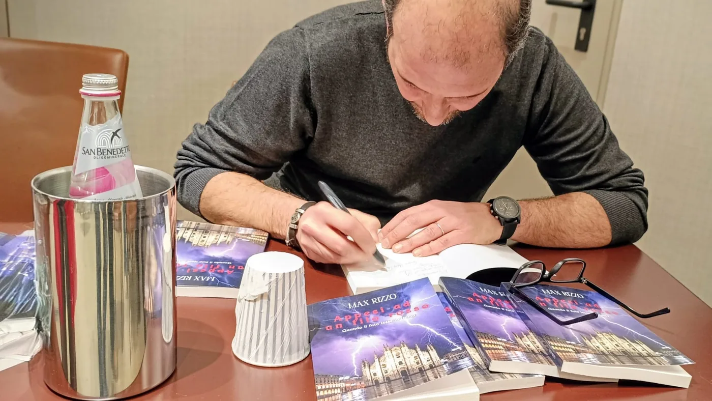 Max Rizzo firma le copie dei suoi libri durante una presentazione